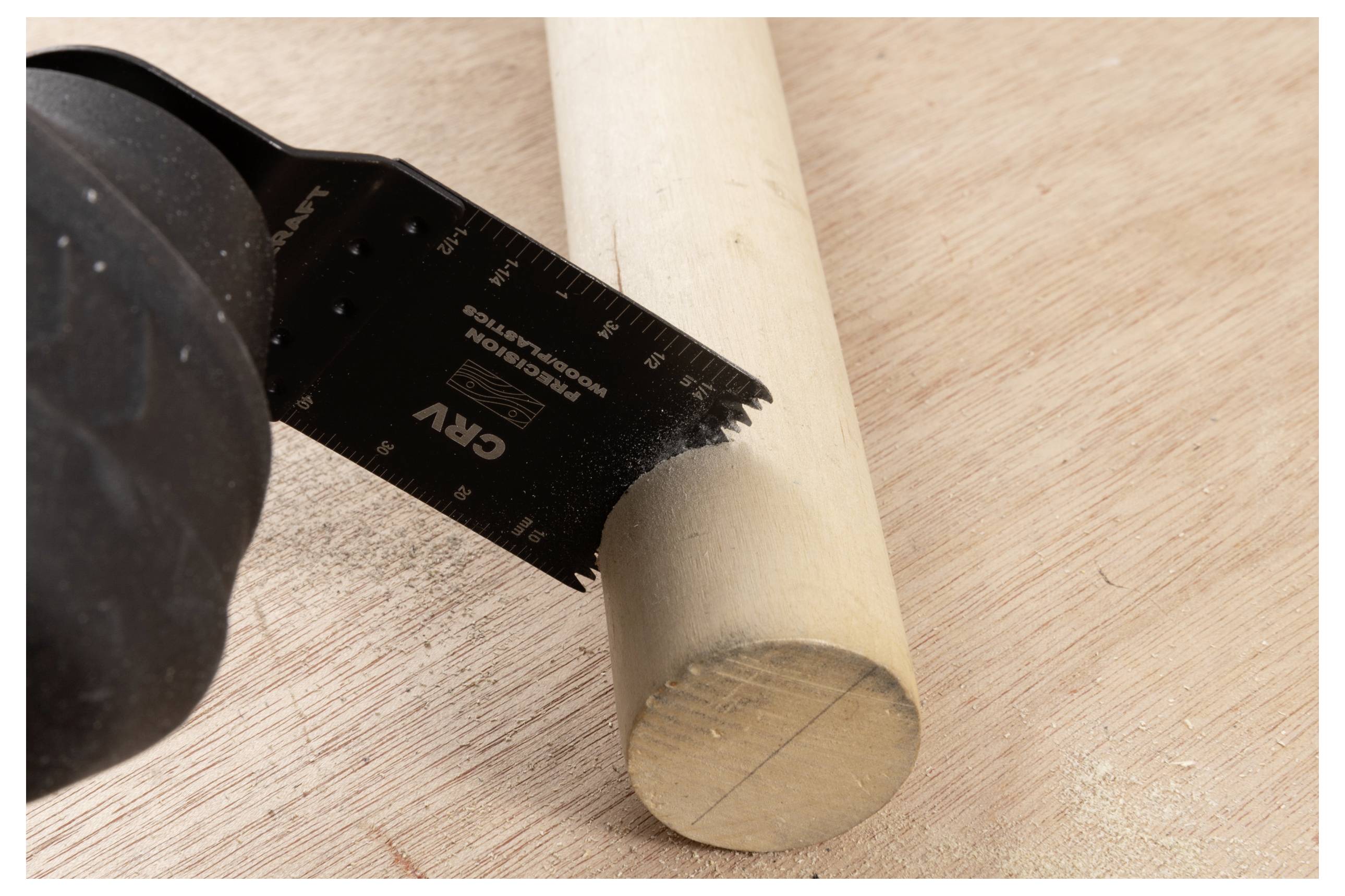 Eine Säge, die einen Holzdübel auf einer Werkbank durchschneidet, mit einem Teil einer behandschuhten Hand, die die Säge hält, zeigt Holzarbeit in Aktion.