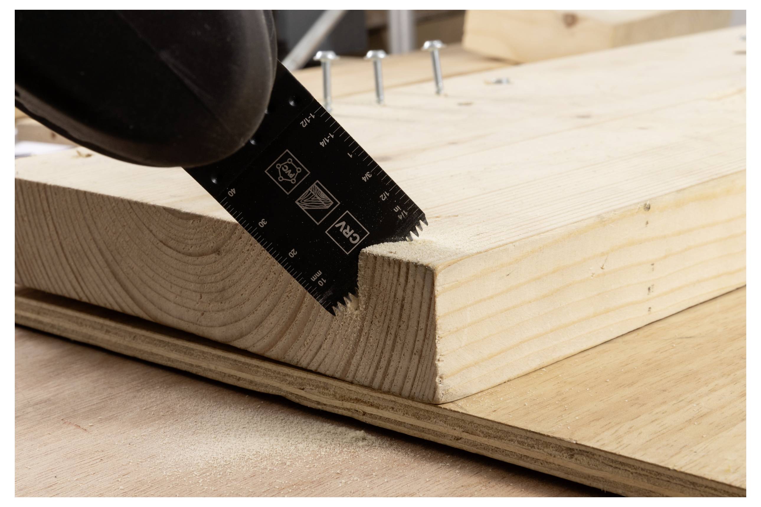 Eine Nahaufnahme einer Sägeblatt, das durch eine Holzplatte schneidet. Mehrere Schrauben liegen auf dem Holz und deuten auf ein aktives Holzbearbeitungsprojekt hin.