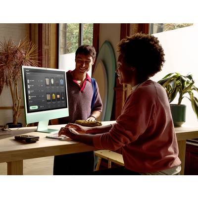 Zwei Personen in einem modernen Büroumfeld arbeiten an einem Desktop-Computer, auf dem eine digitale Planungsbenutzeroberfläche angezeigt wird. Eine Person sitzt, die andere steht daneben.