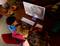 Eine Familie mit drei Personen schaut einen Animationsfilm auf einem Computerbildschirm in einem gemütlichen Wohnzimmer, umgeben von Kissen und Pflanzen.