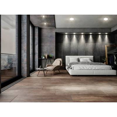 Modernes Schlafzimmer mit grauem Bett, einem Sessel und Tisch. Große Fenster links, bieten Blick nach draußen. Elegant und minimalistisch.
