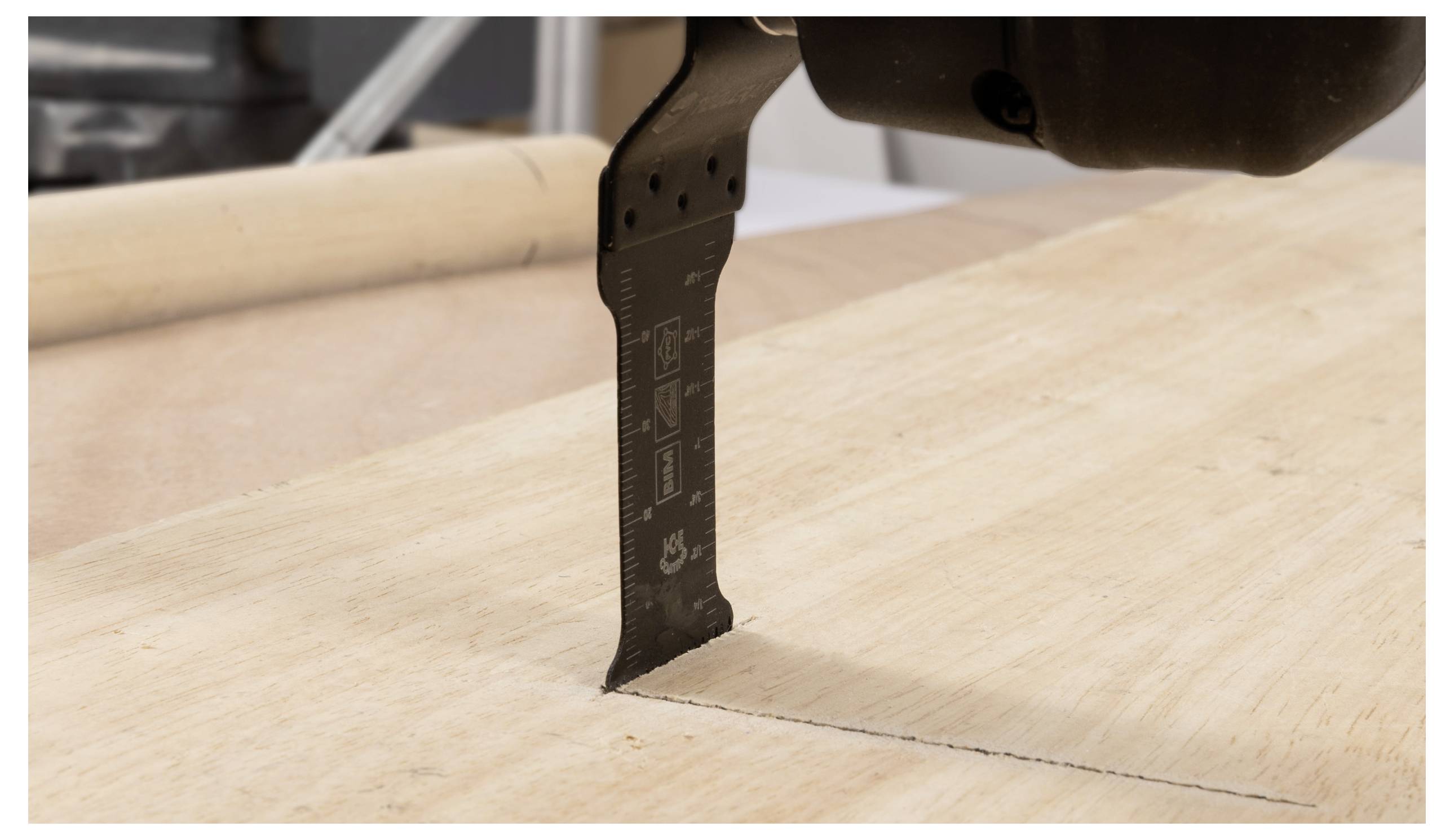 Eine Nahaufnahme eines Multifunktionswerkzeugs mit einem Holzschneidblatt, das entlang einer markierten Linie auf einem Holzbrett aktiv schneidet.