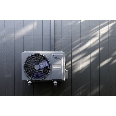 Eine Klimaanlage ist an einer dunklen Wand montiert. Sonnenlicht fällt schräg darauf, und erzeugt leichte Schattenmuster.