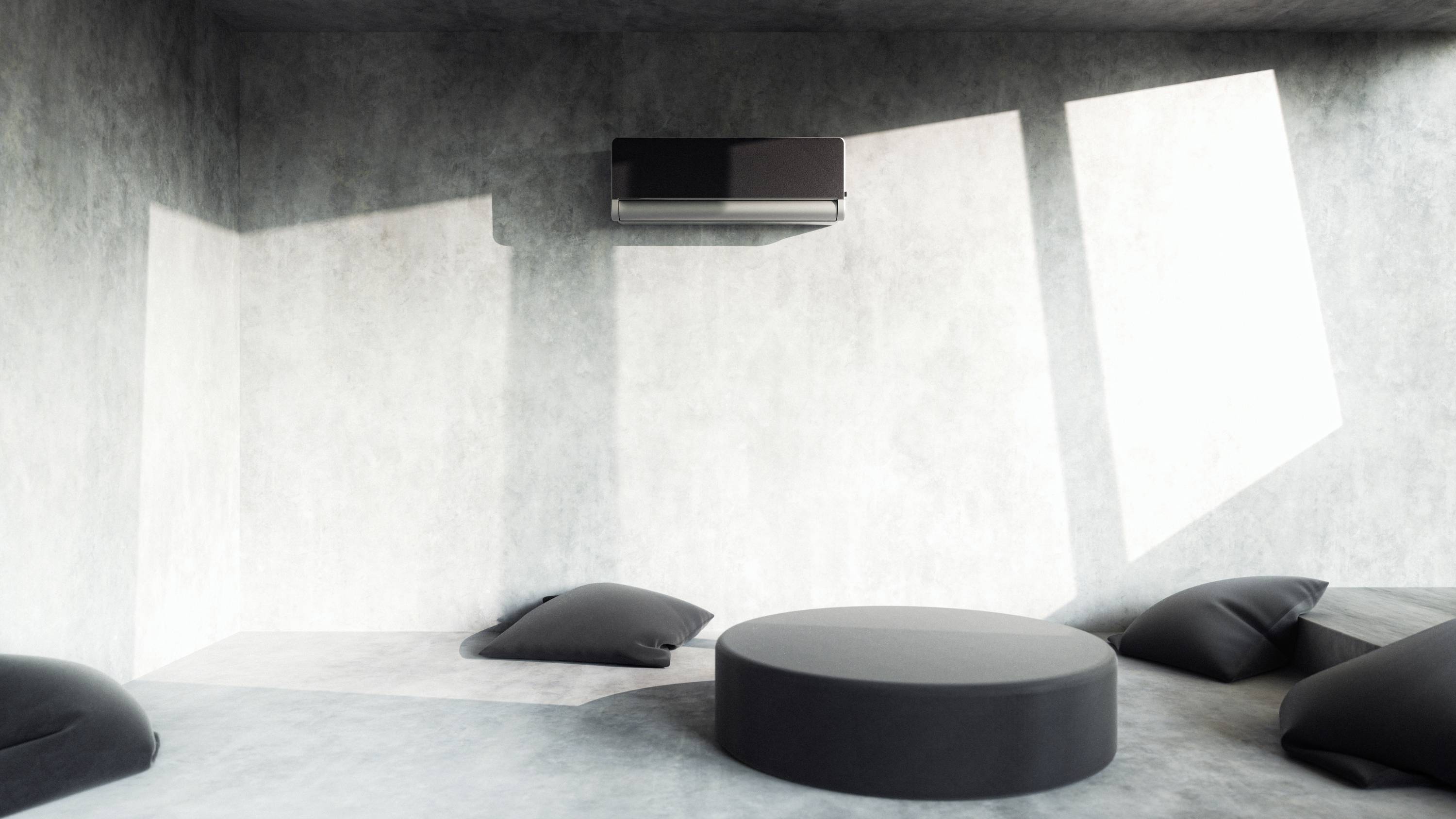 Moderner, minimalistischer Raum mit grauen Wänden, einem schwarzen Luftfilter an der Wand und flachen, schwarzen Kissen auf dem Boden.