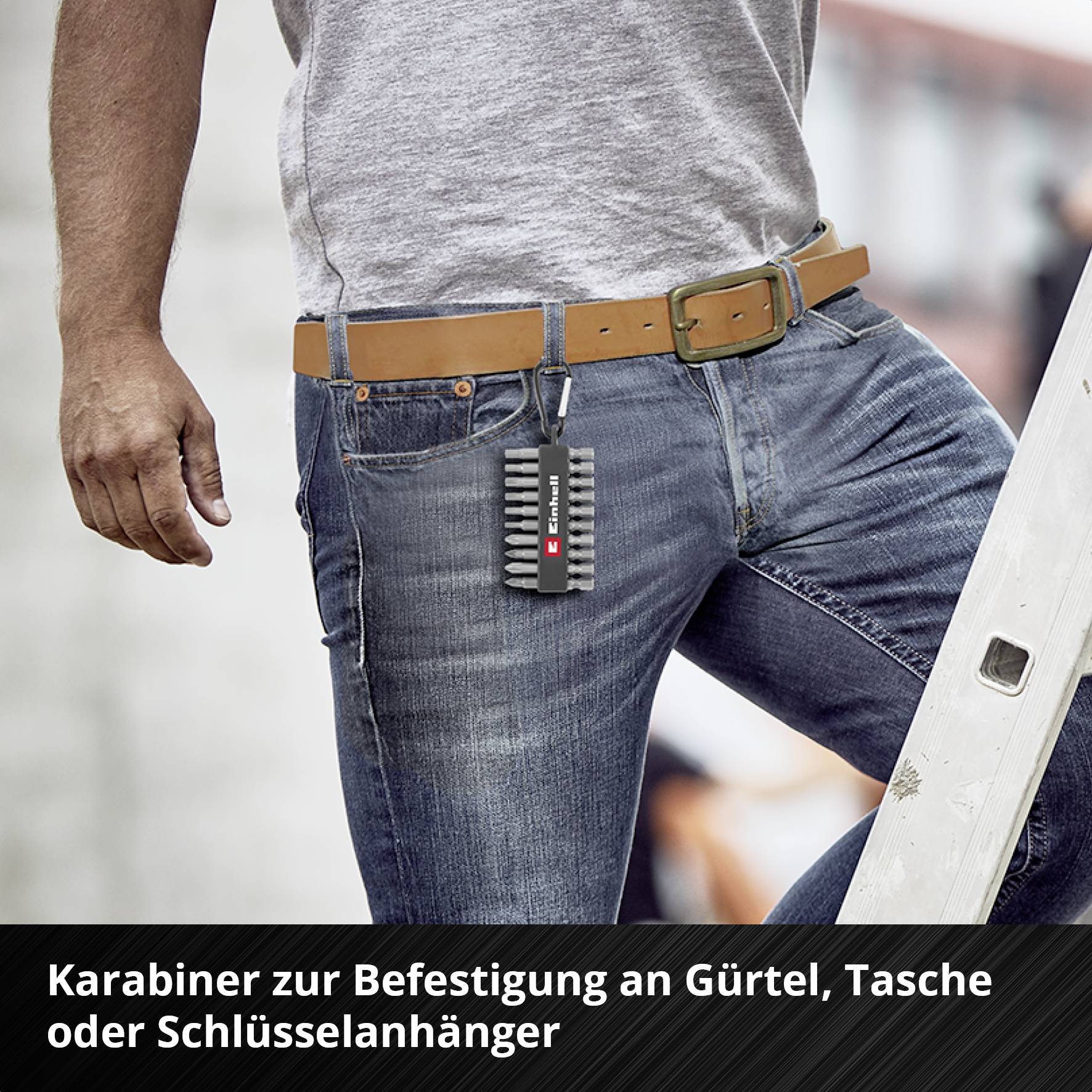 Mann trägt Jeans mit einem Karabinerhaken am Gürtel, der eine kleine Tasche hält. Text auf Tasche: 'E-Titan'.