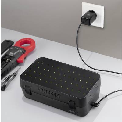 Schwarze VOLTGRAFT-Batteriebox auf einer Werkbank, in eine Wandsteckdose eingestöpselt und wird aufgeladen, mit grünen Statusleuchten und elektrischen Werkzeugen in der Nähe.