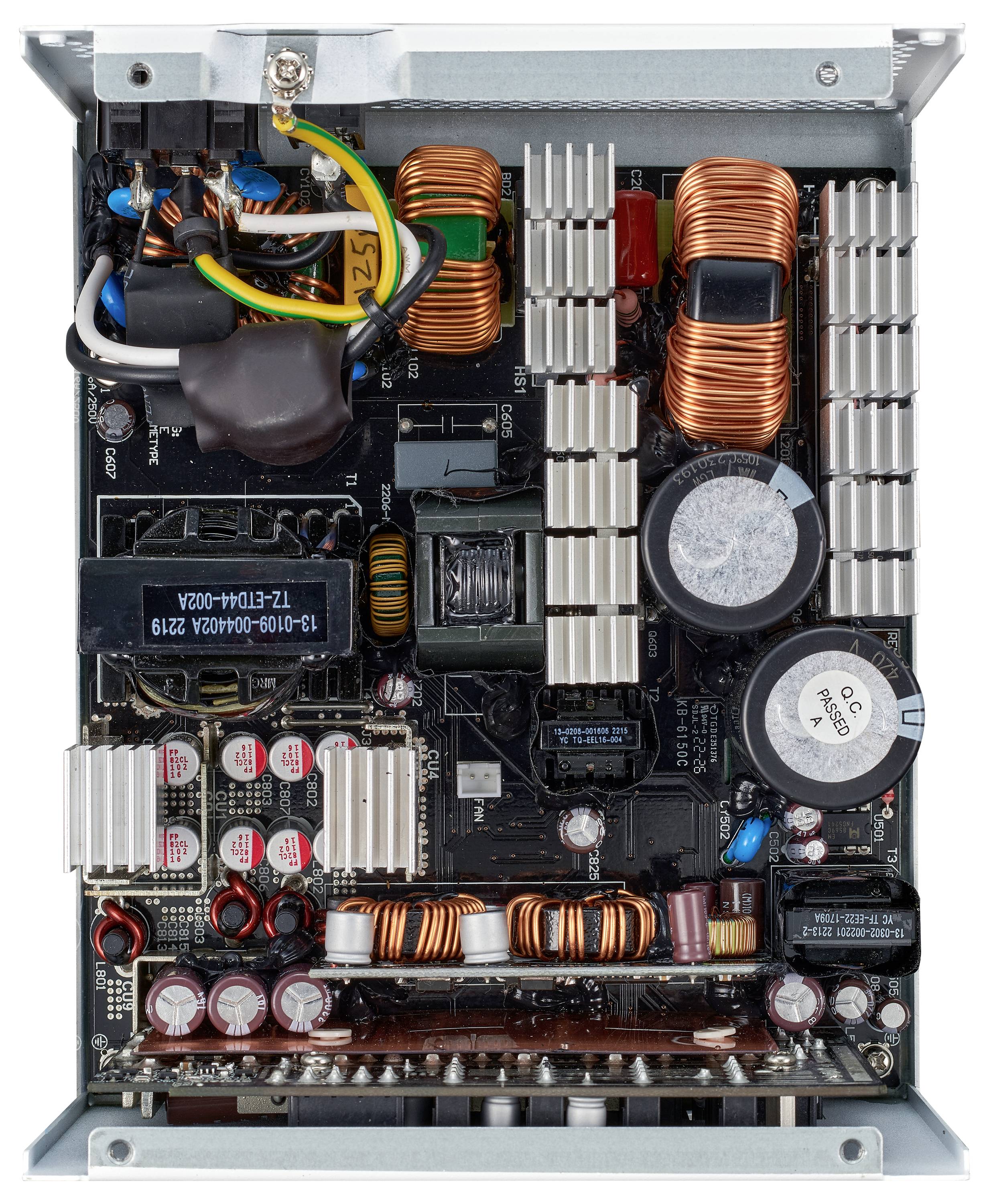 Innere Ansicht eines Computernetzteilgehäuses, die Schaltungskomponenten wie Kondensatoren, Spulen und Kühlkörper auf einer Platine zeigt.