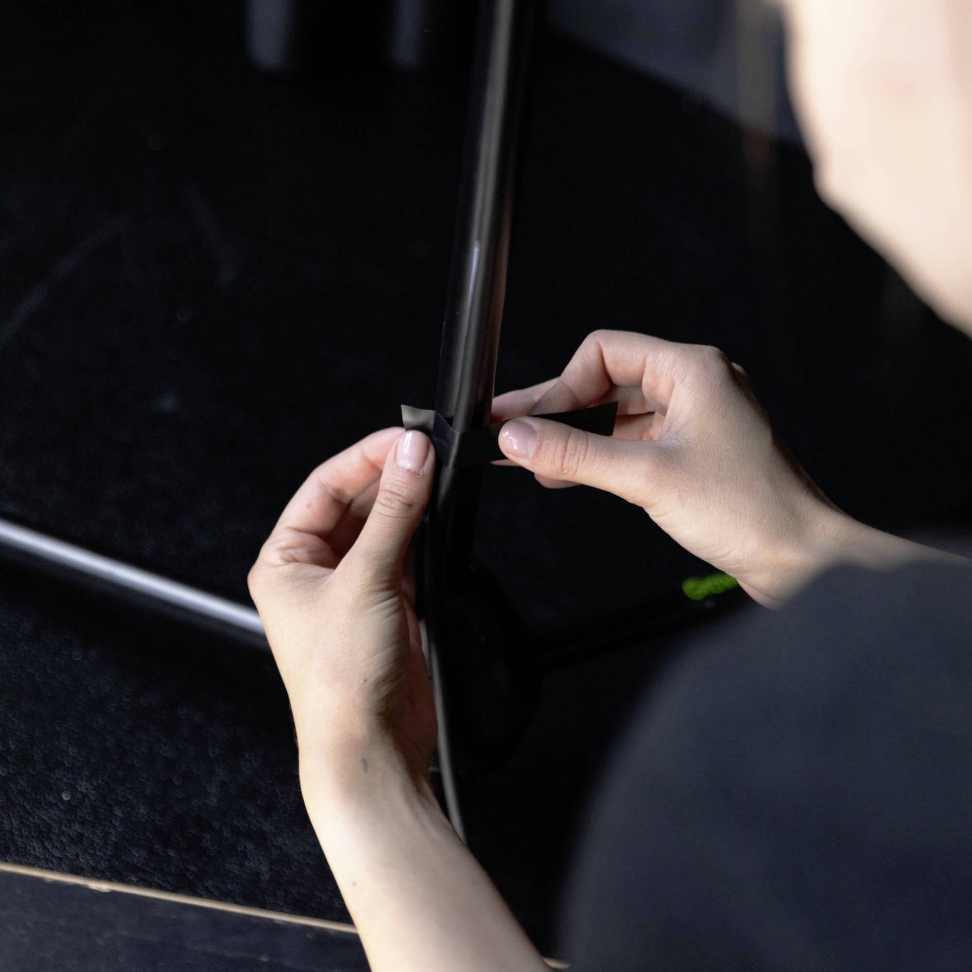 Eine Person befestigt ein kleines Stück schwarzes Band an einem dünnen Metallstab.