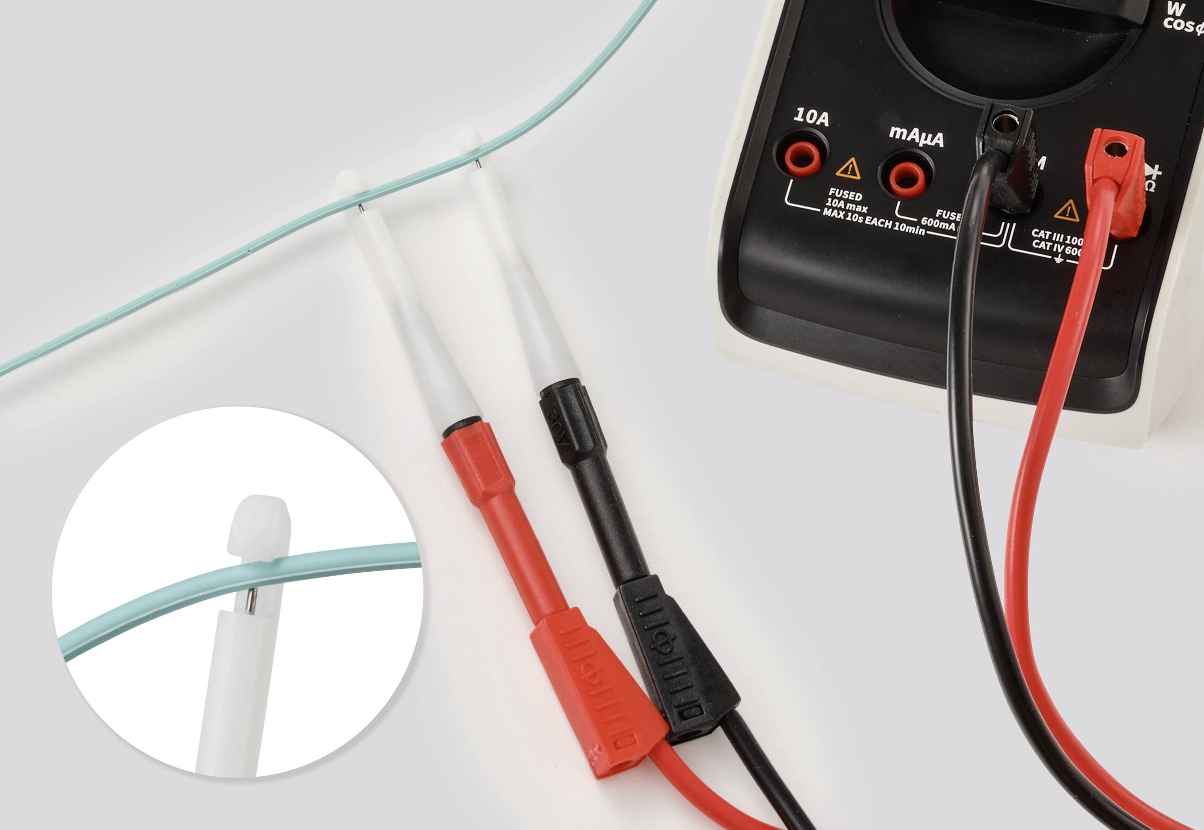 Multimeter-Prüfkabel testen einen blauen Draht. Der rote Prüfkabel berührt ein Drahtende; der schwarze Prüfkabel berührt das gegenüberliegende Ende.