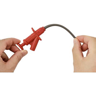 Eine Person hält eine rote Messleitung mit den Händen und bereitet sich darauf vor, sie zur Prüfung oder Messung mit einem elektronischen Gerät zu verbinden.