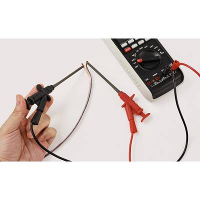Eine Hand verwendet ein Multimeter, um die Spannung zwischen zwei freigelegten Kabeln zu messen und zeigt dabei elektrische Messung oder Fehlersuche.