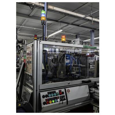 Automatisierte Industriemaschine auf einer Fertigungslinie mit blinkenden grünen, gelben und roten Statusleuchten sowie Bedienungstasten im Vordergrund.