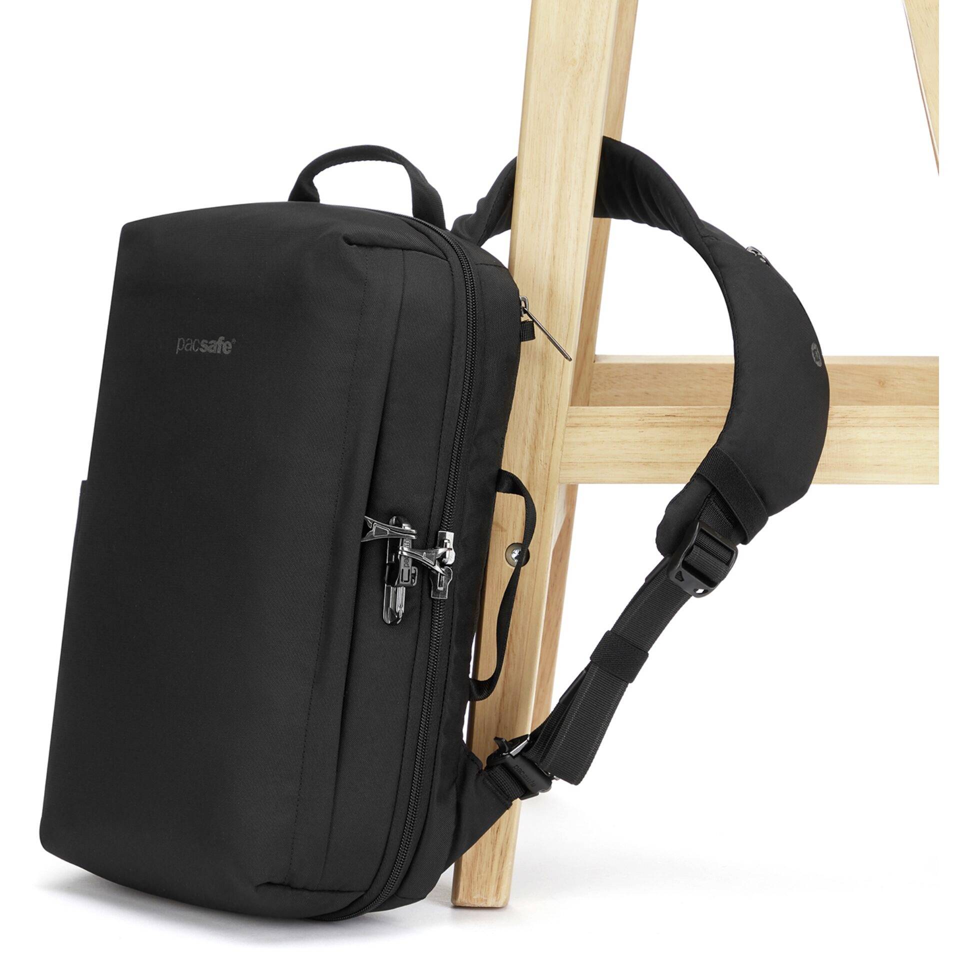 Ein schwarzer Rucksack, der mit einem Diebstahlschutzschloss an einem Holzstuhl gesichert ist und Diebstahlprävention veranschaulicht.