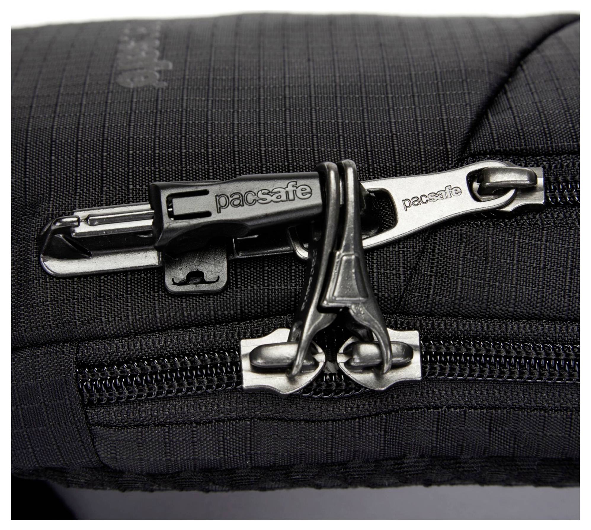 Nahaufnahme eines schwarzen Reißverschlussabschnitts aus Stoff mit einem 'Pacsafe' markierten Reißverschluss. Der Stoff weist ein strukturiertes Gittermuster und einen Sicherheitsclip auf.