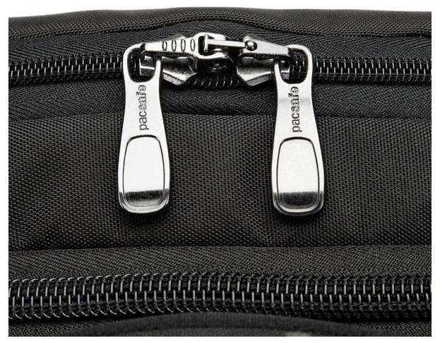 Nahaufnahme einer schwarzen Stofftasche mit zwei silbernen Reißverschlüssen, auf denen der Markenname 'pacsafe' eingraviert ist und eine sichere Verschließung demonstriert wird.