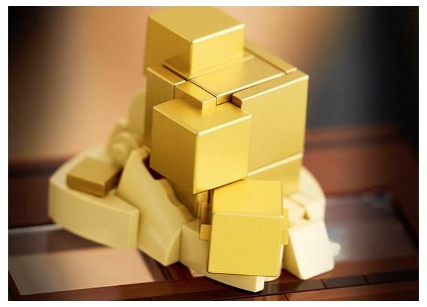 Ein skulpturales Werk mit gestapelten goldenen Würfeln auf einer abstrakten, felsigen Basis, die einen geometrischen Kontrast zu den glatten, glänzenden Würfeln schafft.