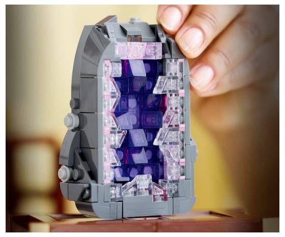 Eine Hand, die ein buntes LEGO-Stück zusammenbaut und dabei detaillierte transparente und lila Elemente auf einer dunkelgrauen Konstruktion zeigt.