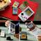 Eine Sammlung von Game Boy-Konsolen und Spielmodulen auf einem Tisch, die ikonische Spiele präsentiert. Menschen berühren die Geräte und rufen ein Gefühl der Nostalgie hervor.