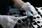 Eine Person mit weißen Handschuhen misst einen Metallblock mit einem Mikrometerschrauber und konzentriert sich dabei auf Präzision und Genauigkeit in einer Werkstattumgebung.
