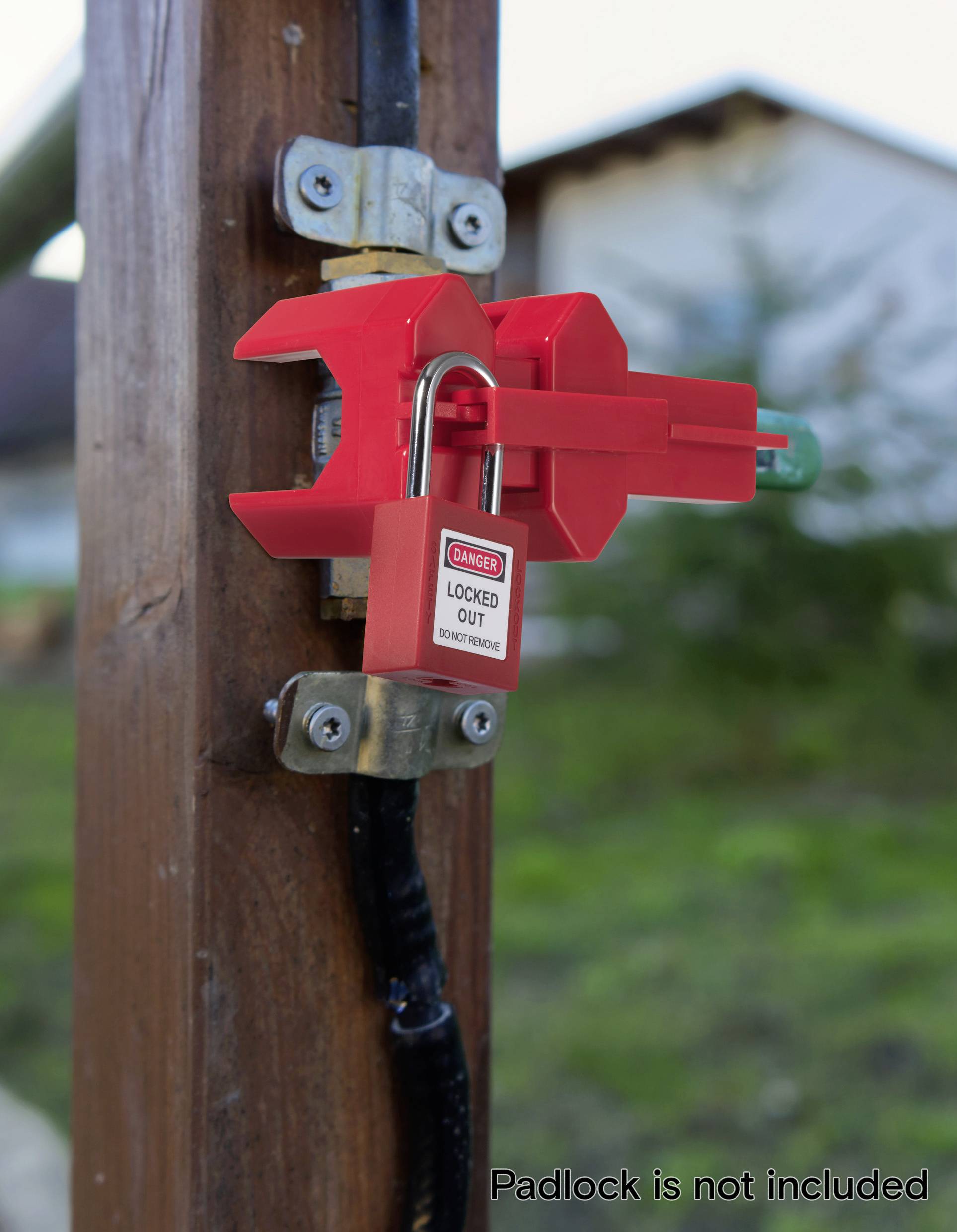 Ein rotes Sperrgerät klemmt sich auf einen Elektroschalter und sichert ihn mit einem Vorhängeschloss, auf dem "Gefahr: Gesperrt" steht. Der Hintergrund ist unscharf.