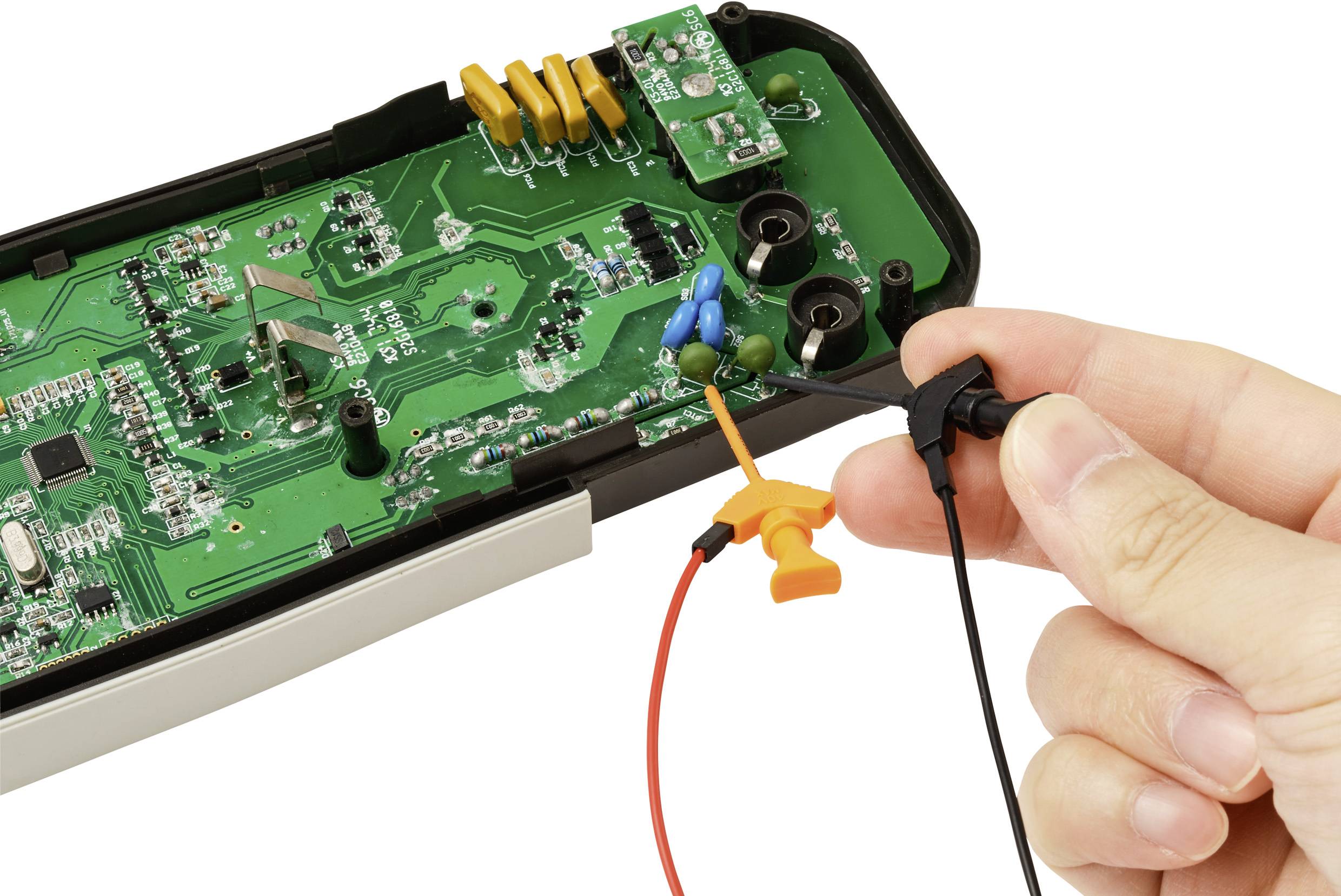 Eine Hand hält eine Sonde, die mit der internen Leiterplatte eines elektronischen Geräts verbunden ist und eine Nahaufnahme seiner Komponenten und Verkabelung zeigt.