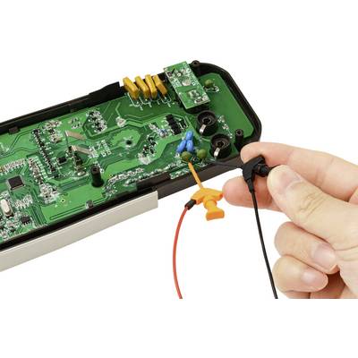 Eine Hand hält eine Sonde, die mit der internen Leiterplatte eines elektronischen Geräts verbunden ist und eine Nahaufnahme seiner Komponenten und Verkabelung zeigt.