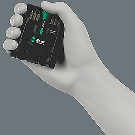 Eine Hand hält einen kompakten Wiha Werkzeugkoffer mit einem grüngriffigen Schraubendreher und mehreren auswechselbaren Bits vor einem schlichten Hintergrund.