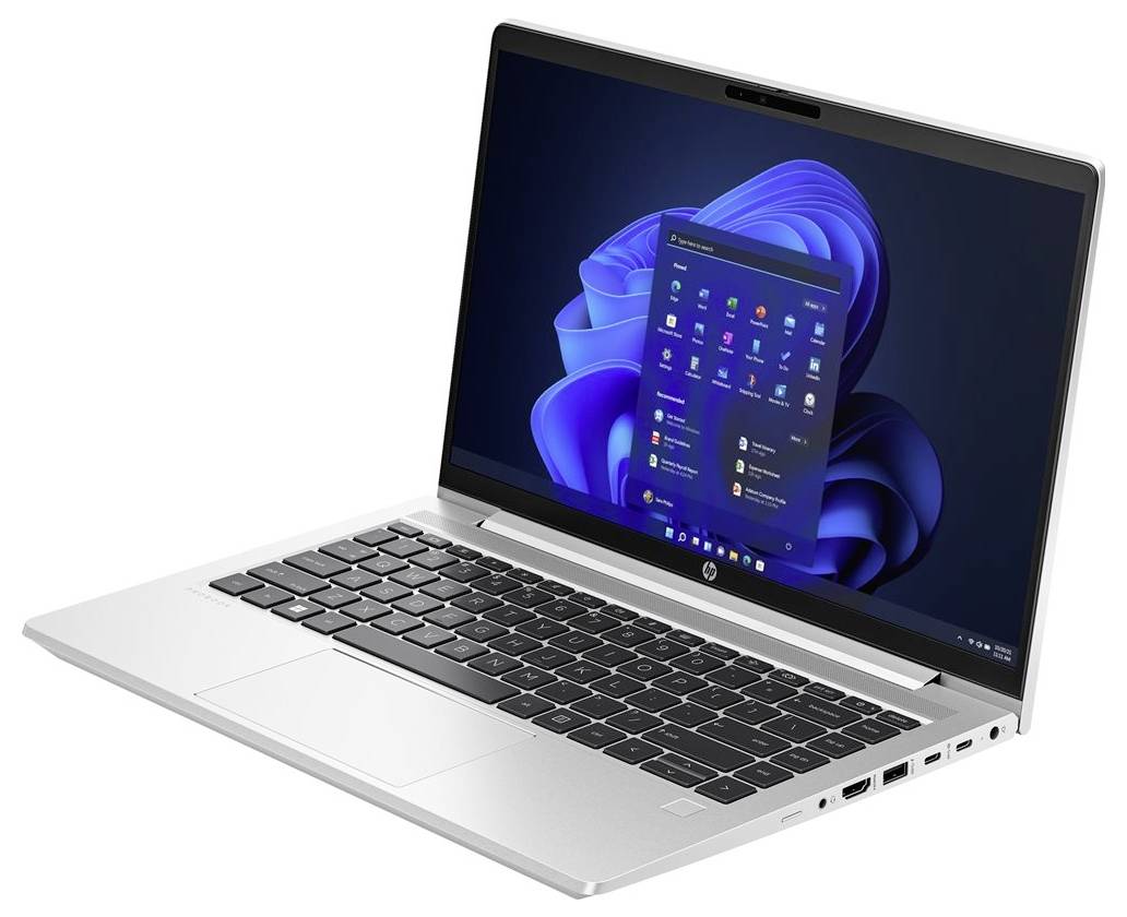 Ein silberner Laptop, der den Windows 11 Startbildschirm mit verschiedenen Anwendungssymbolen zeigt, der auf einem schwarzen und blauen abstrakten Hintergrund platziert ist.