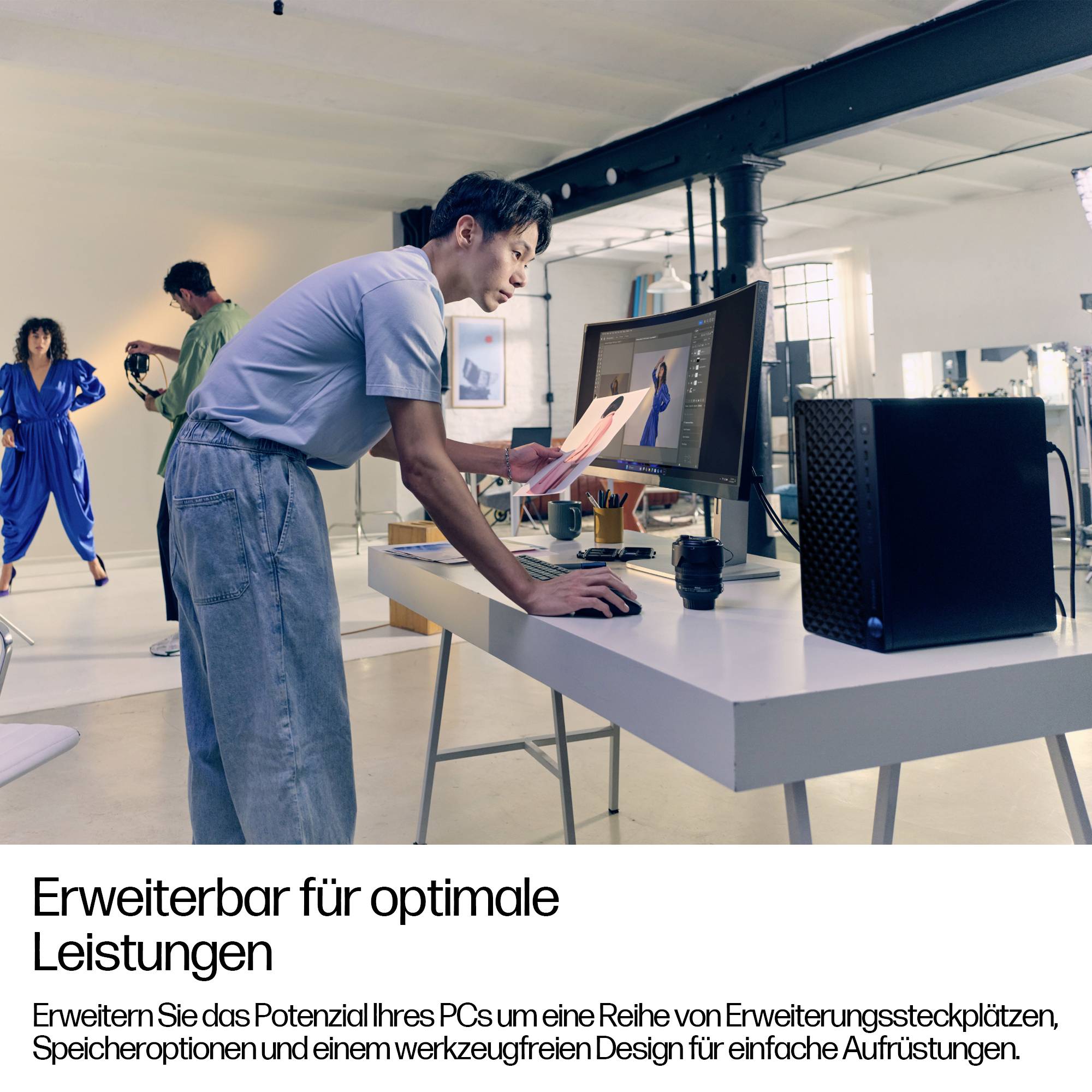 Eine Person in einem Büroumfeld bewertet ein Design auf einem großen Computermonitor. Ein Kollege im Hintergrund interagiert mit Geräten. Text lautet: 'Erweiterbar für optimale Leistungen.'