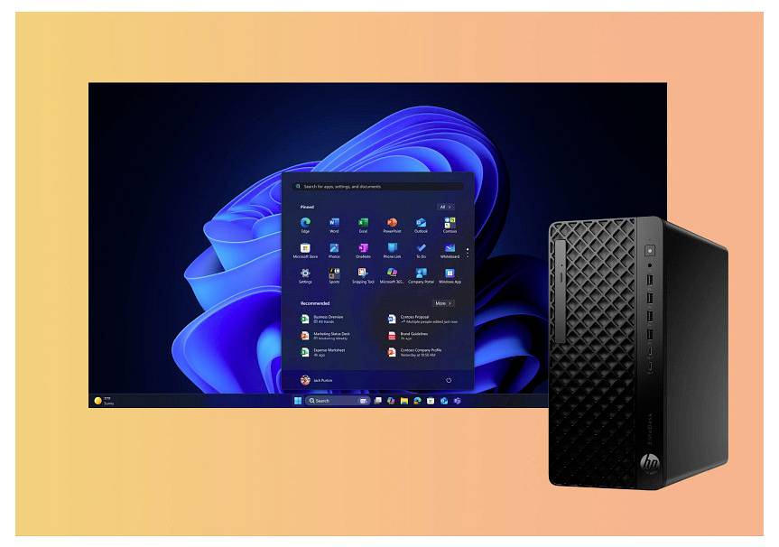 Ein schwarzer Desktop-Computer neben einem Monitor, der einen blauen Betriebssystembildschirm mit verschiedenen hervorgehobenen Anwendungssymbolen zeigt.