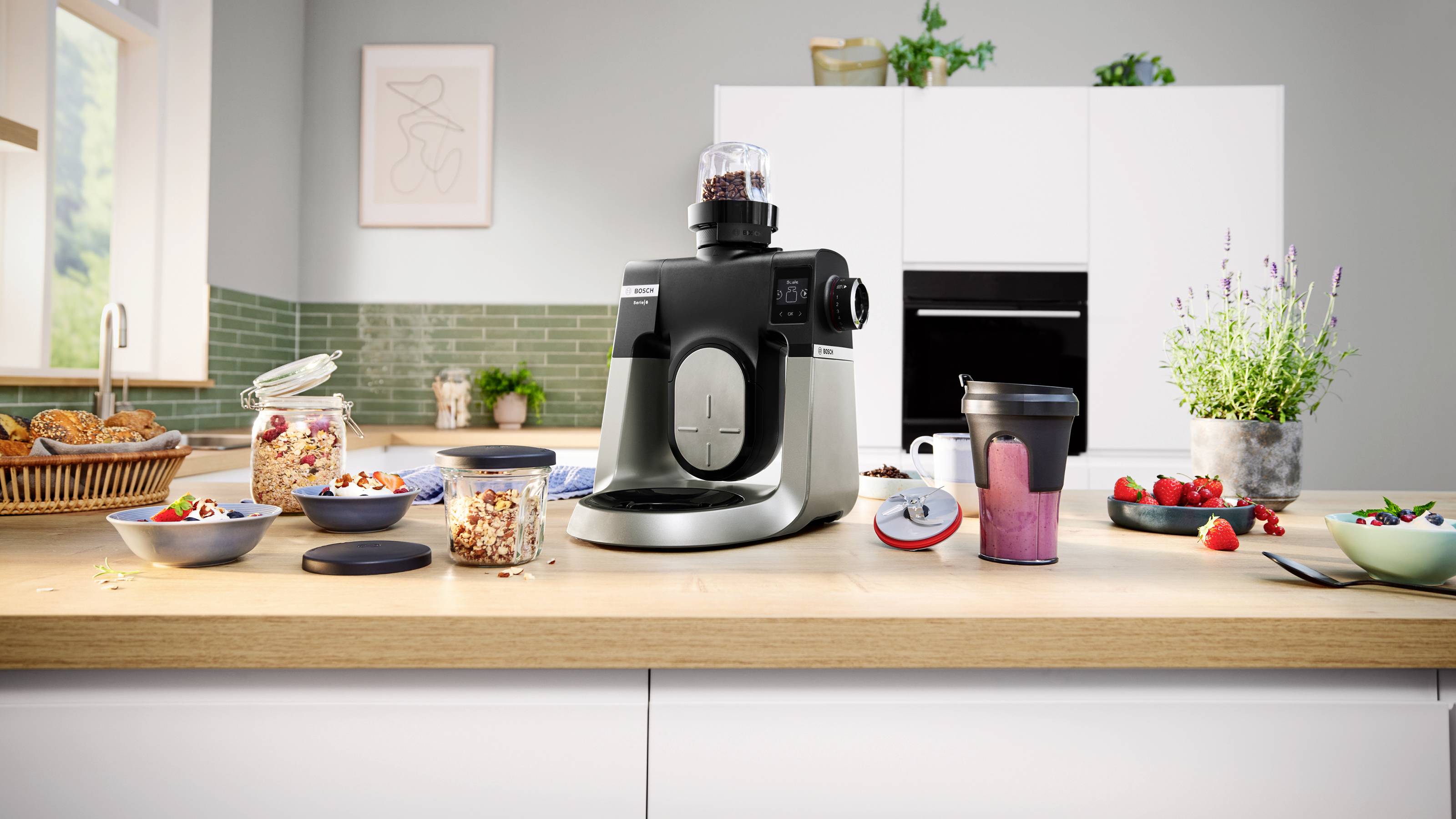 Eine Küchenarbeitsplatte mit einer Kaffeemühle, umgeben von Frühstücksartikeln wie Beeren, Müsli und Saft, die eine Morgenroutine andeuten.