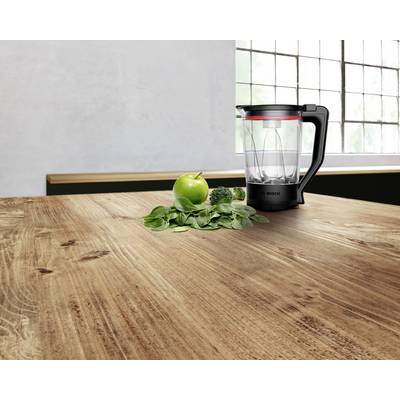 Ein Mixer mit einem durchsichtigen Behälter steht auf einem Holztisch neben Spinat, einem Apfel und Brokkoli, was die Vorbereitung eines Smoothies andeutet.