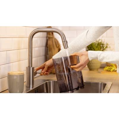 Eine Person füllt einen Wasserbehälter unter einem Küchenhahn, wobei das Wasser durch das undurchsichtige Design des Wasserkrugs als gefiltert gekennzeichnet ist, platziert auf einer modernen Arbeitsplatte.
