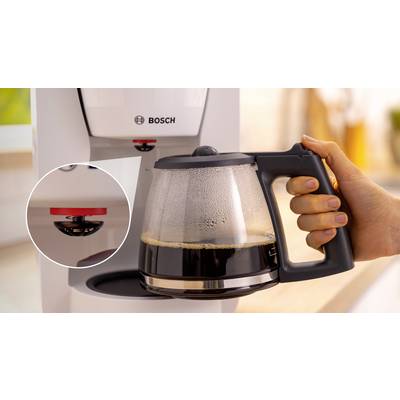 Eine Hand platziert eine Kaffeekanne mit frisch gebrühtem Kaffee in einen Bosch-Kaffeevollautomat. Ein rotes Bedienungselement wird hervorgehoben.