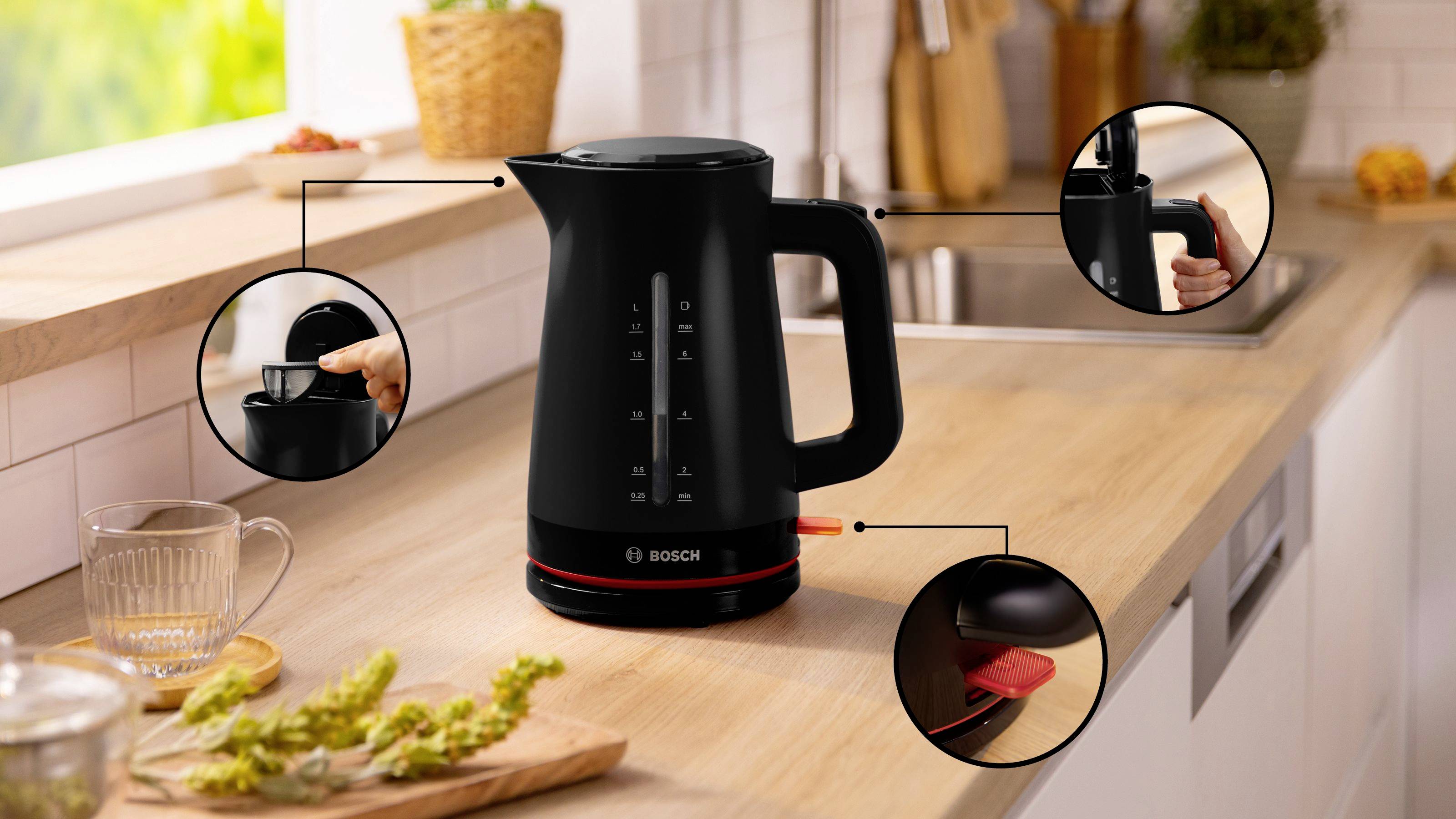 Schwarzer elektrischer Wasserkocher auf einer Küchenarbeitsplatte mit beschrifteten Merkmalen: ergonomischer Griff, Drucktastenverschluss und Betriebsanzeigelampe.