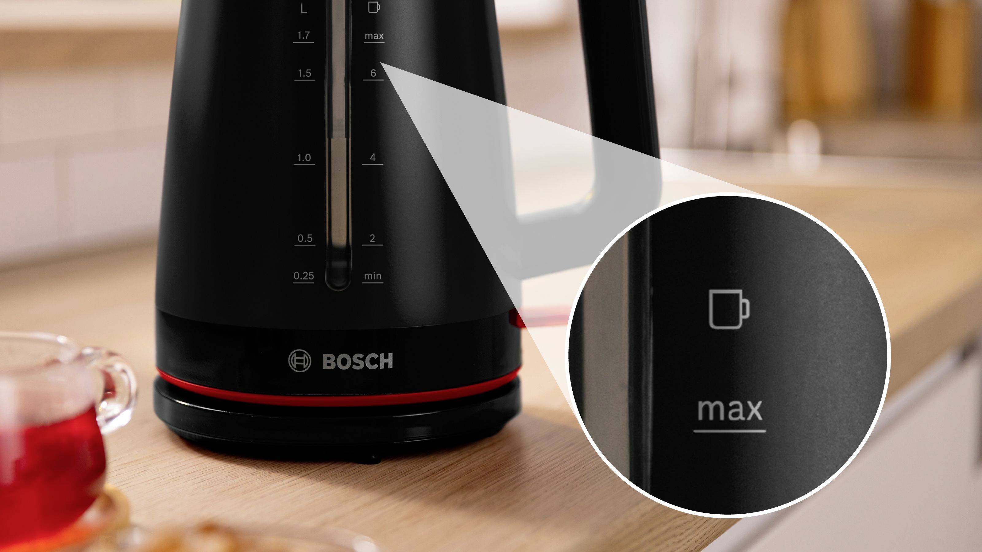 Ein schwarzer Bosch-Wasserkocher auf einer Holztheke, mit hervorgehobenen Messniveaus und angezeigter 'max'-Markierung sowie einem roten Indikator.