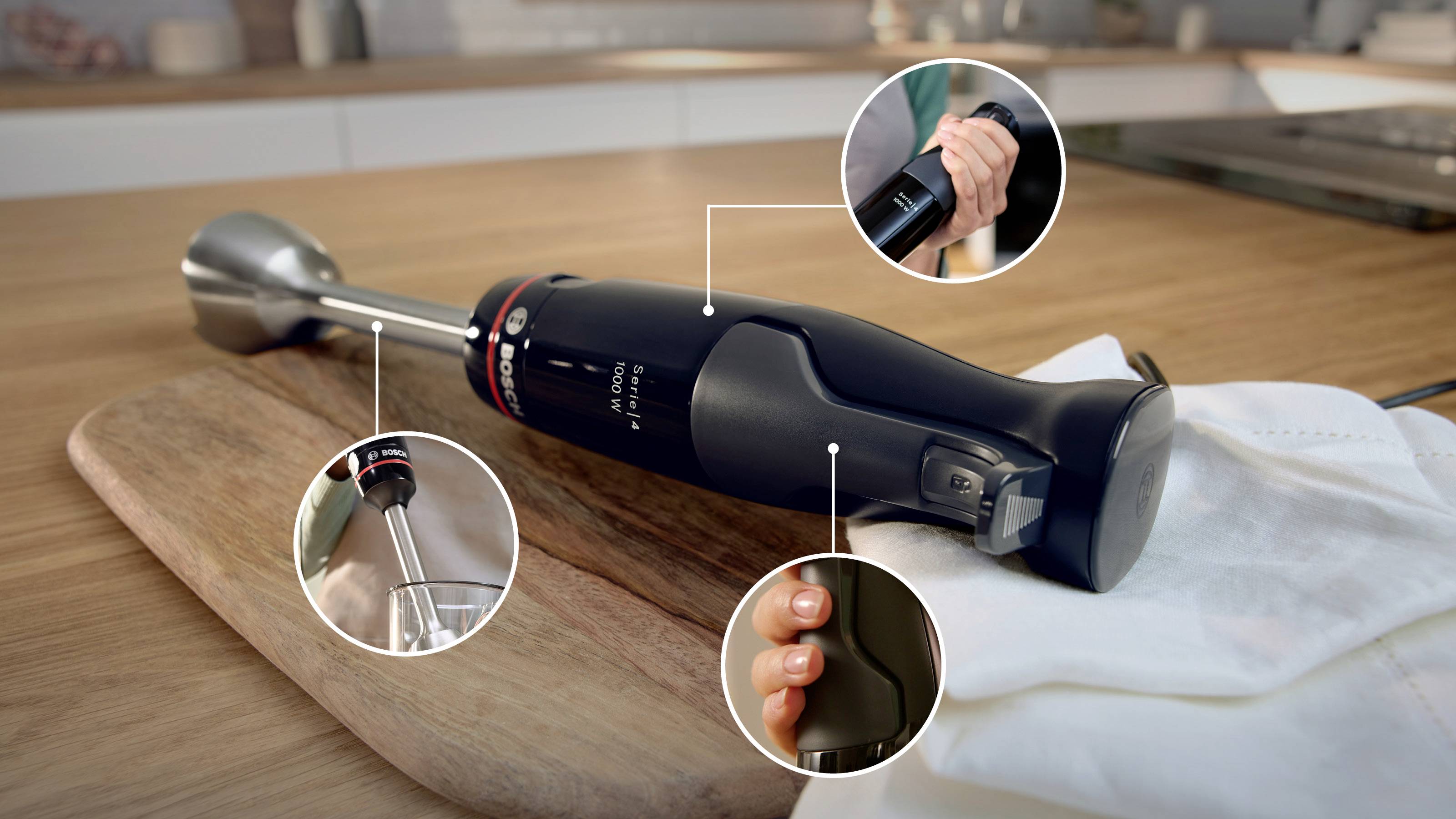 Stabmixer auf einer Holzarbeitsplatte, mit Nahaufnahmen des Einschaltknopfs, der Geschwindigkeitseinstellung und des abnehmbaren Quiraufsatzes.