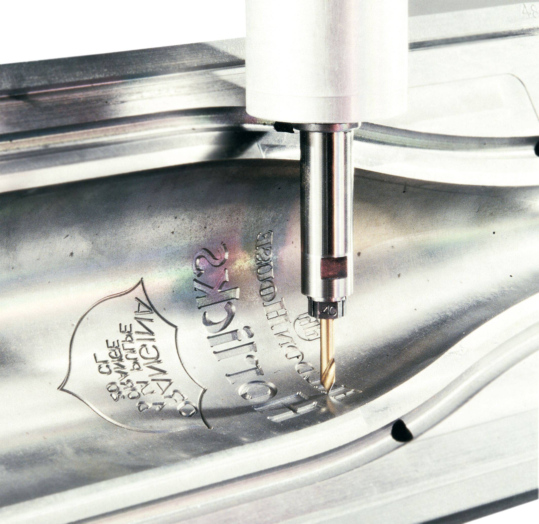 Eine CNC-Maschine graviert Text in eine Metalloberfläche und demonstriert dabei präzise industrielle Fertigungsfähigkeiten.