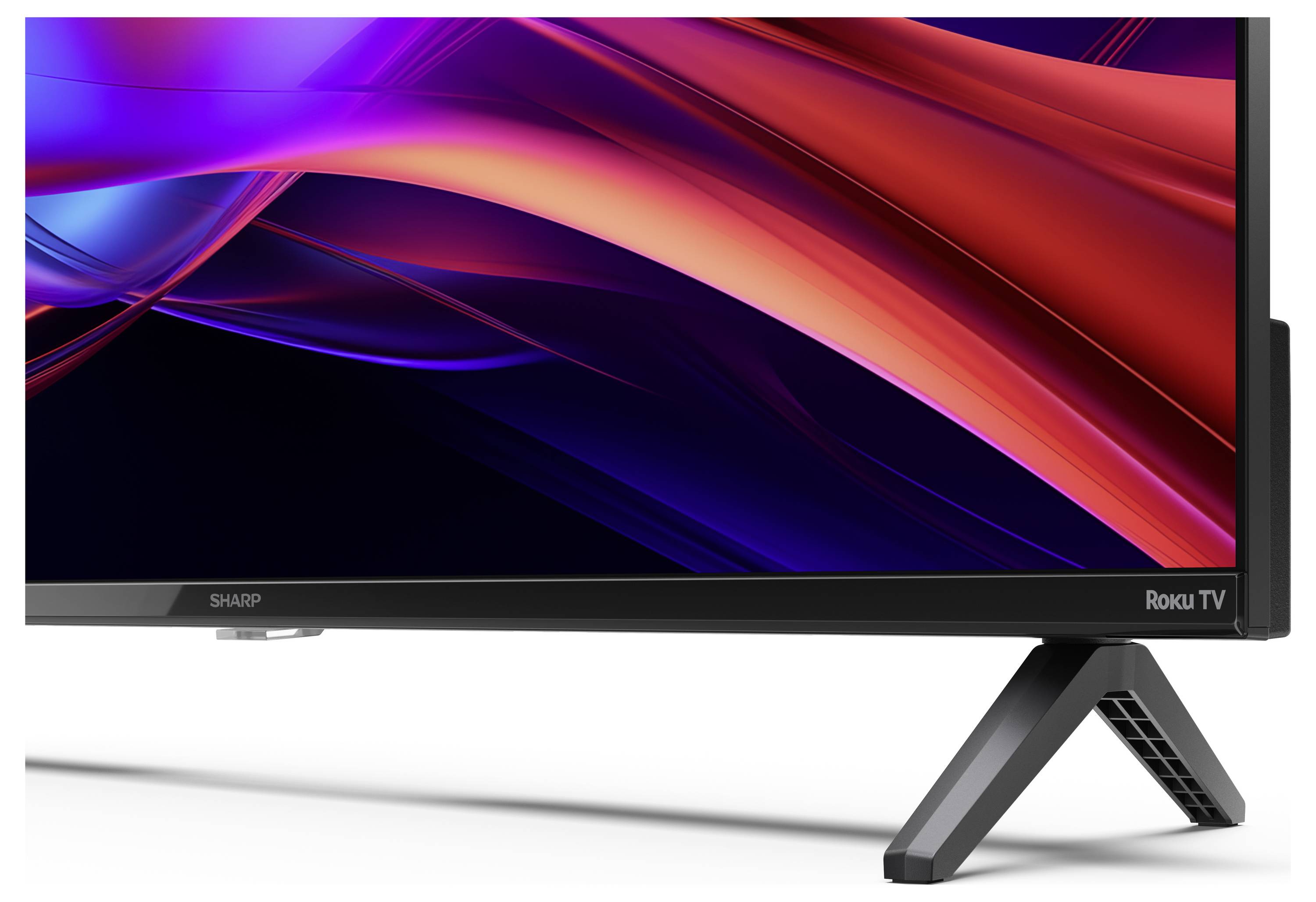 Eine Nahaufnahme der Ecke eines Sharp Roku Fernsehers, die einen eleganten schwarzen Rahmen und einen modernen Standfuß zeigt, und sein stilvolles Design betont.
