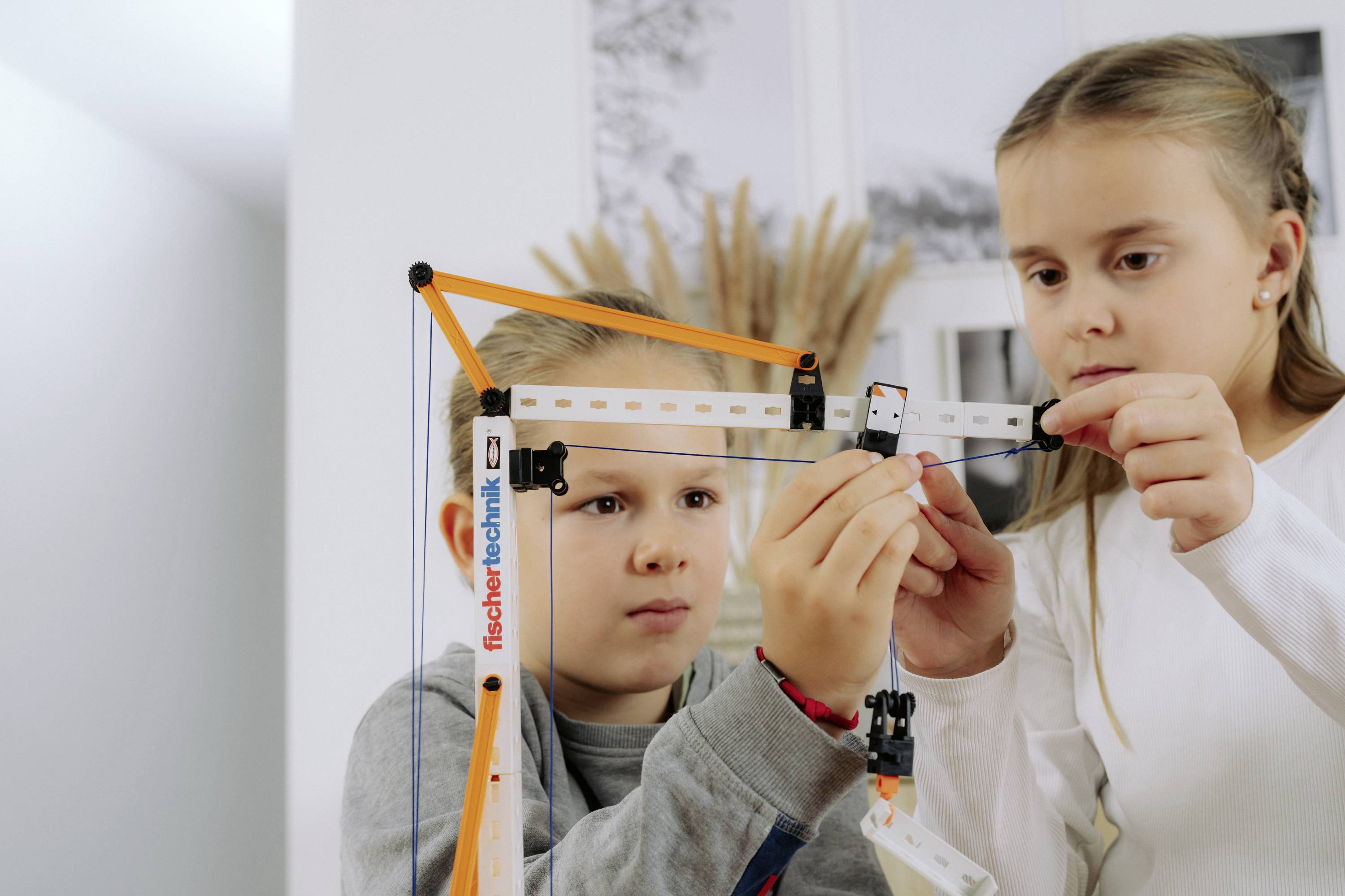 Zwei Kinder konzentrieren sich darauf, einen Konstruktionssatz zusammenzubauen und arbeiten gemeinsam daran, die Teile zu verbinden.