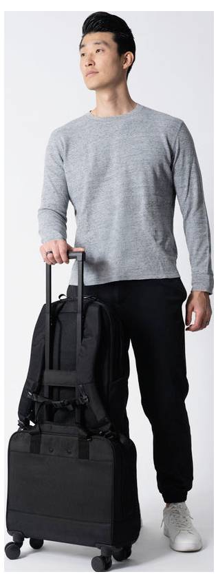 Nahaufnahme einer Person, die ein schwarzes Rucksack-Tragesystem über einem weißen Hemd trägt, mit einem Brustgurt, der über die Vorderseite befestigt ist.