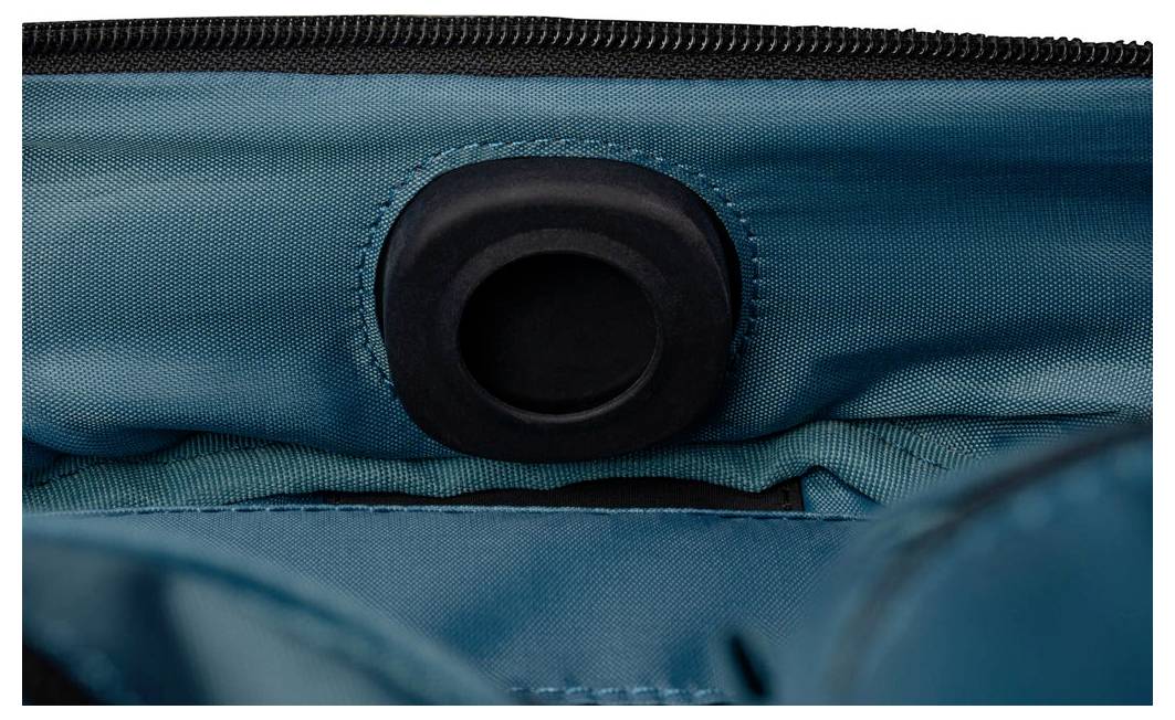 Nahaufnahme einer türkisfarbenen Stoff-Tasche mit einer schwarzen, kreisförmigen Öse oder Öffnung in der Nähe des oberen Reißverschlusses.