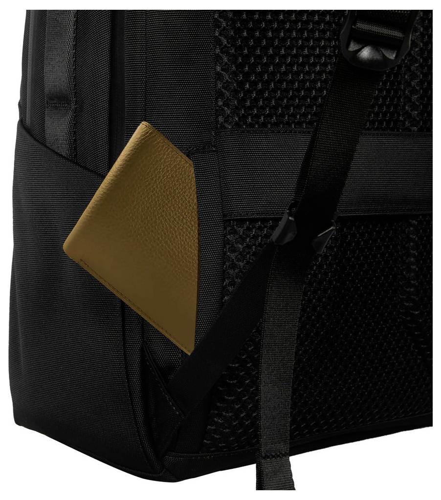 Nahaufnahme eines schwarzen Rucksacks mit beigefarbenem, lederähnlichem Eckakzent, Riemen und strukturiertem Stoffpanel.