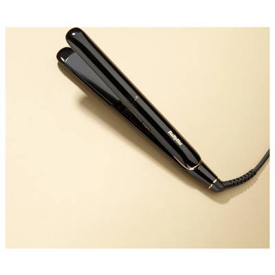 Ein schwarzer Haarglätter liegt auf einer beigen Oberfläche und zeigt sein schlankes Design und sein Kabel.