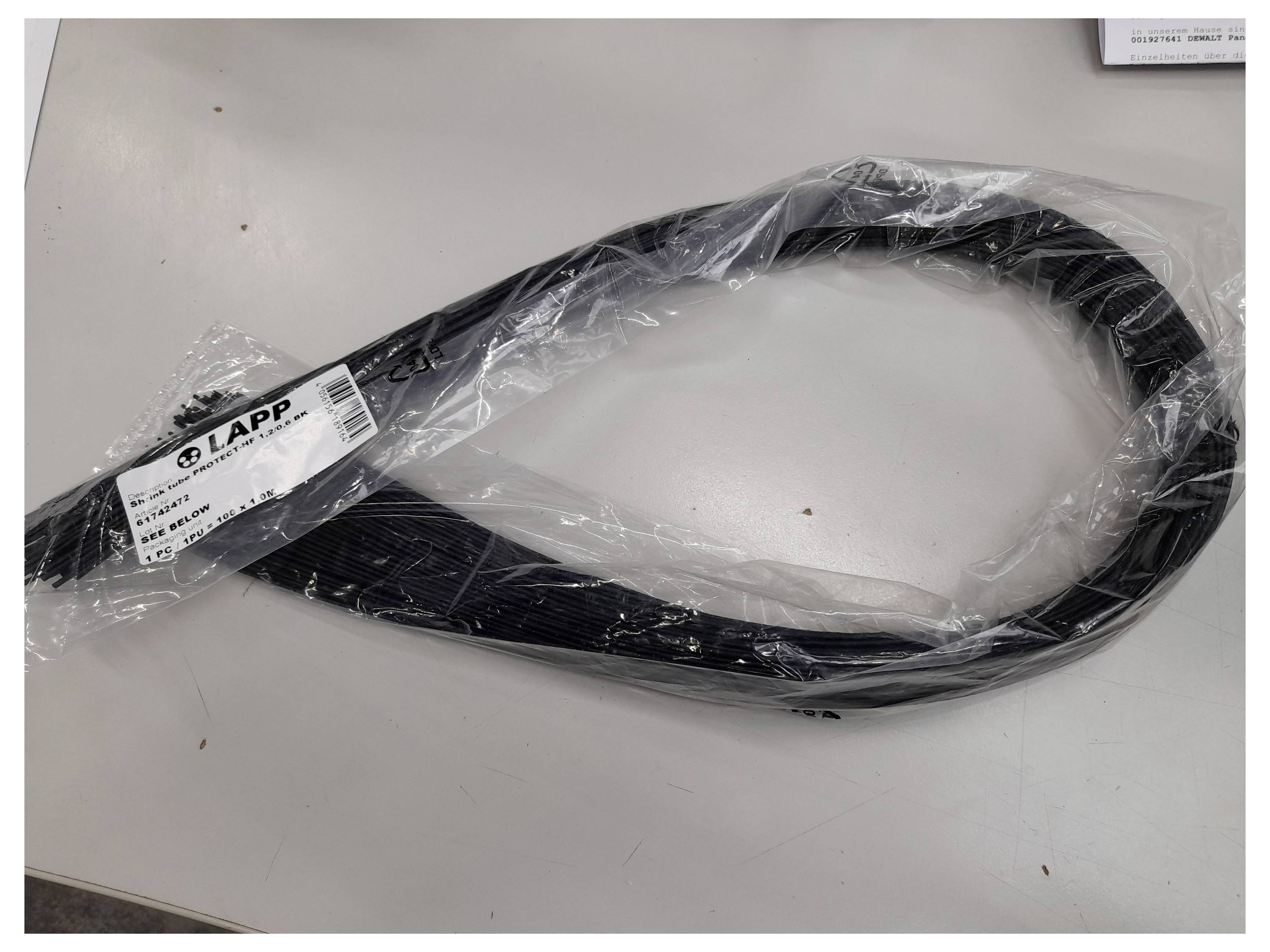 Aufgerolltes schwarzes Kabel in durchsichtiger Kunststoffverpackung auf einem weißen Tisch mit angebrachtem LAPP-Etikett.