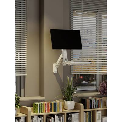 Ein Computermonitor ist an einem verstellbaren Arm befestigt, der an einer Wand über einem Bücherregal mit Büchern und Pflanzen montiert ist, neben einem Fenster mit Jalousien.