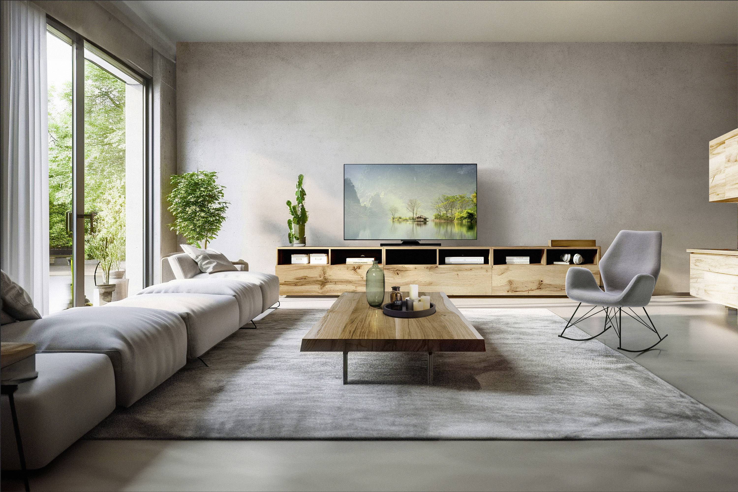 Ein modernes Wohnzimmer mit einem großen Flachbild-Fernseher, einem weißen Sofa, einem Holzcouchtisch und einem grauen Sessel. Sonnenlicht fällt durch eine Glastür herein.