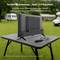 Ein Fernseher auf einem Outdoor-Tisch, mit einem 12V-Adapter, demonstriert seine Mobilität für Reisen. Ein Campingbus ist im Hintergrund zu sehen.