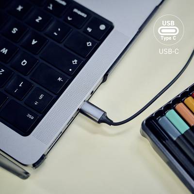 Ein USB Typ-C-Kabel ist an einen Laptop angeschlossen, umgeben von bunten Markern auf einem Schreibtisch, was die Vielseitigkeit von USB-C-Anschlüssen unterstreicht.