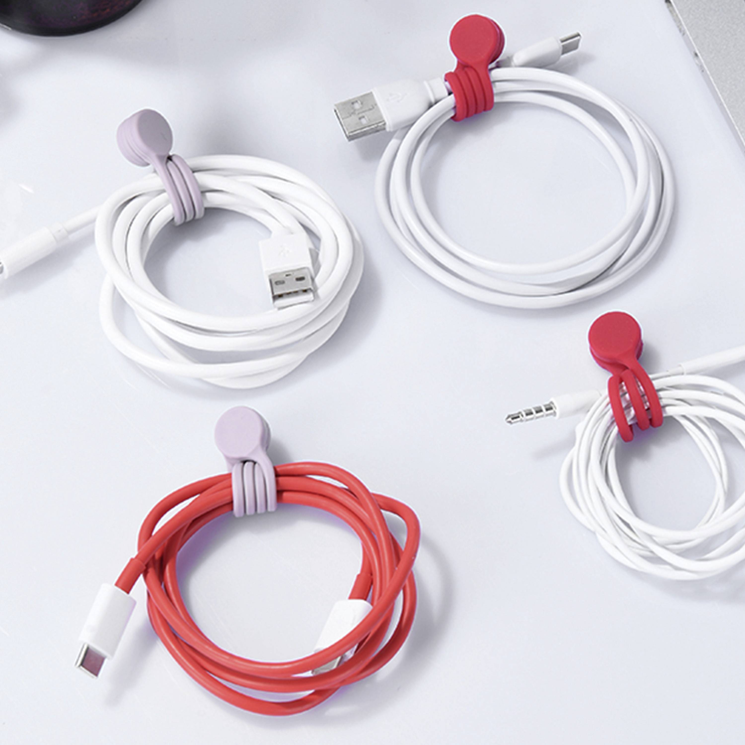 Vier gewickelte Kabel, mit roten und lila Klammern auf einer weißen Oberfläche organisiert; beinhaltet USB- und Audioklinkenstecker.